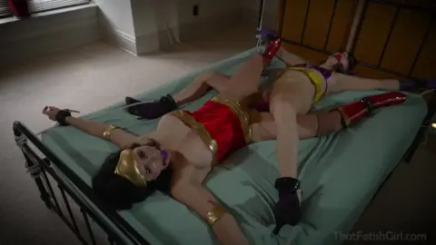 Two brunette chicks tied up while masked guys watch in dungeon room