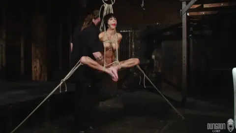Two slim Asian girls and a white guy in rope bondage warehouse scene